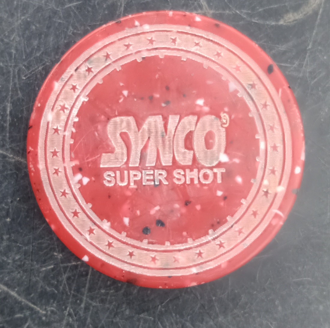 A red SYNCO carrom striker, the disc players flick to pocket coins